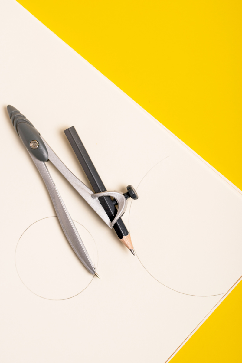 Compass Pencil with Paper on Yellow Background